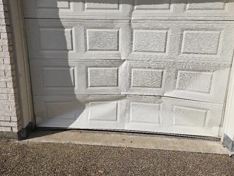 A garage door with dented, buckled panels