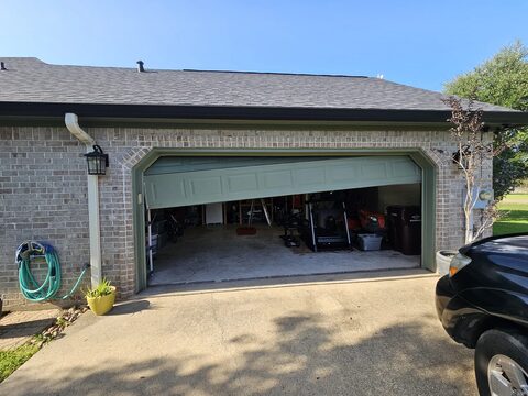 A garage door hanging crooked off its track