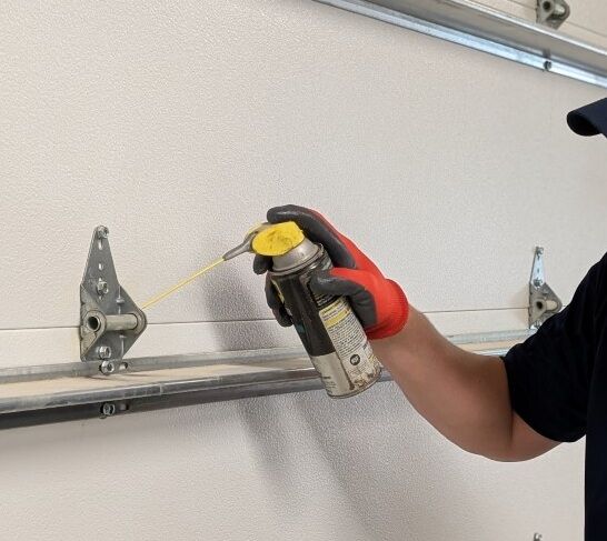 Howdy Garage Doors technician lubricating garage door hinges