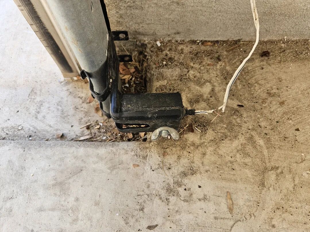 Garage door safety sensor mounted low beside the track