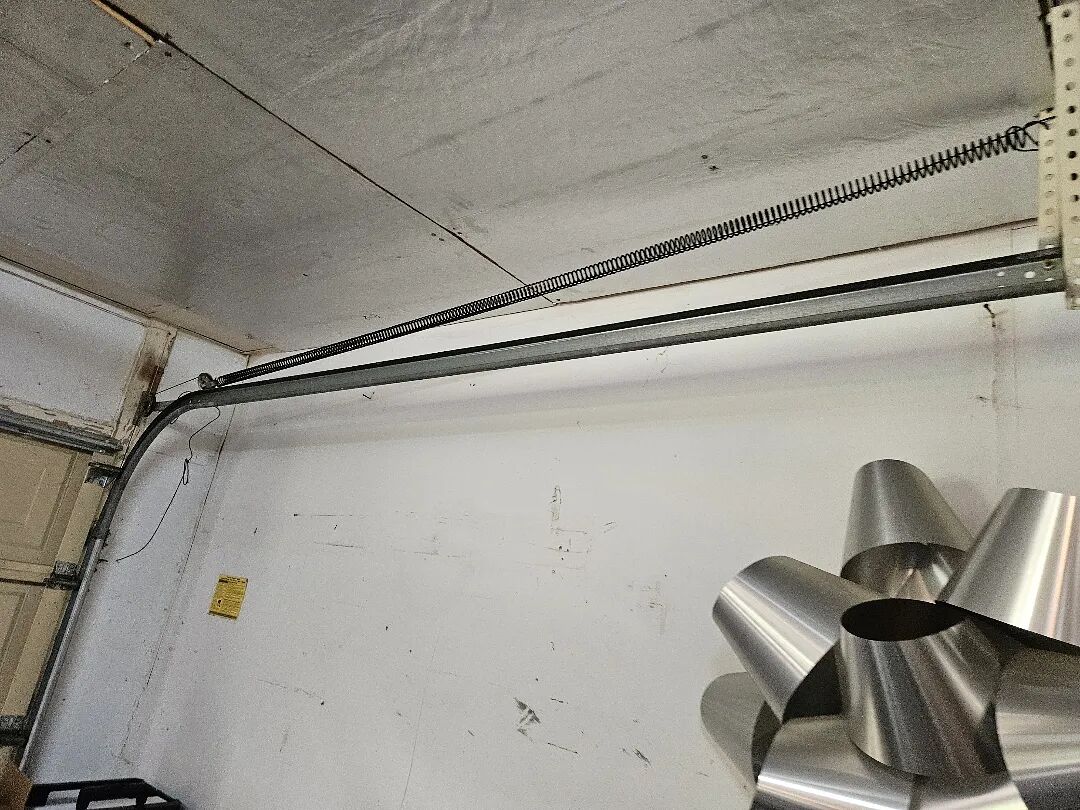 Extension spring running beside the horizontal track of a garage door
